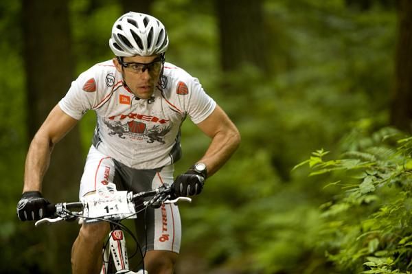 Dağ bisikleti sürücüsü yeşil ormanda zorlu parkurda ilerliyor