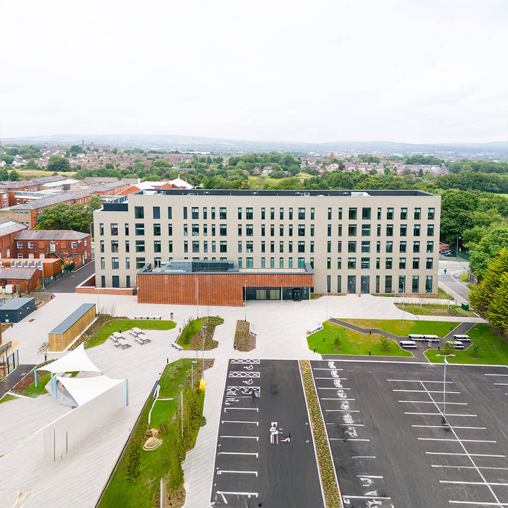 Bolton Üniversitesi'nin modern kampüs binası ve çevresi, yeşil alanlarla zenginleştirilmiş.