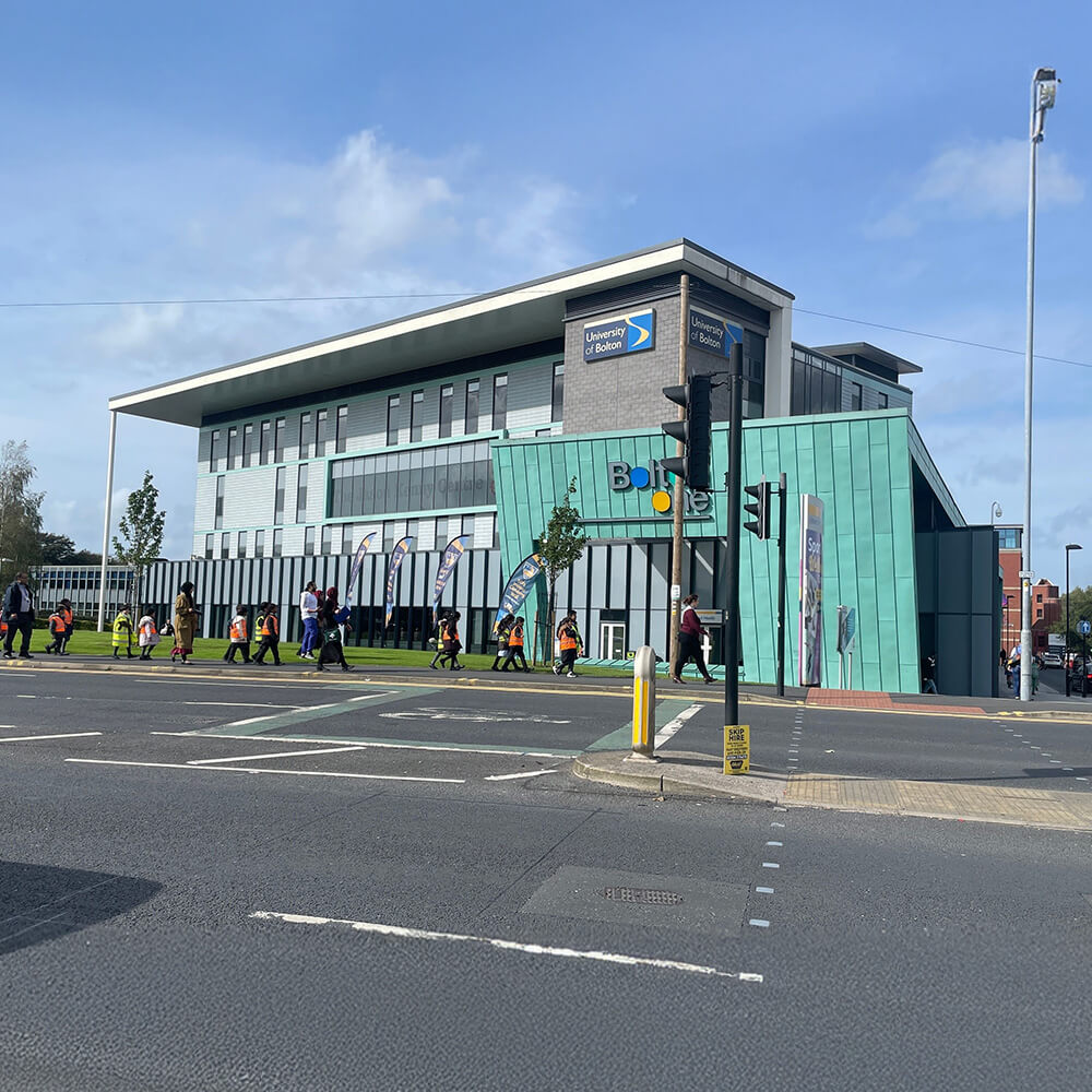 Bolton Üniversitesi binası, öğrenci grupları dışarıda yürüyüş yapıyor.